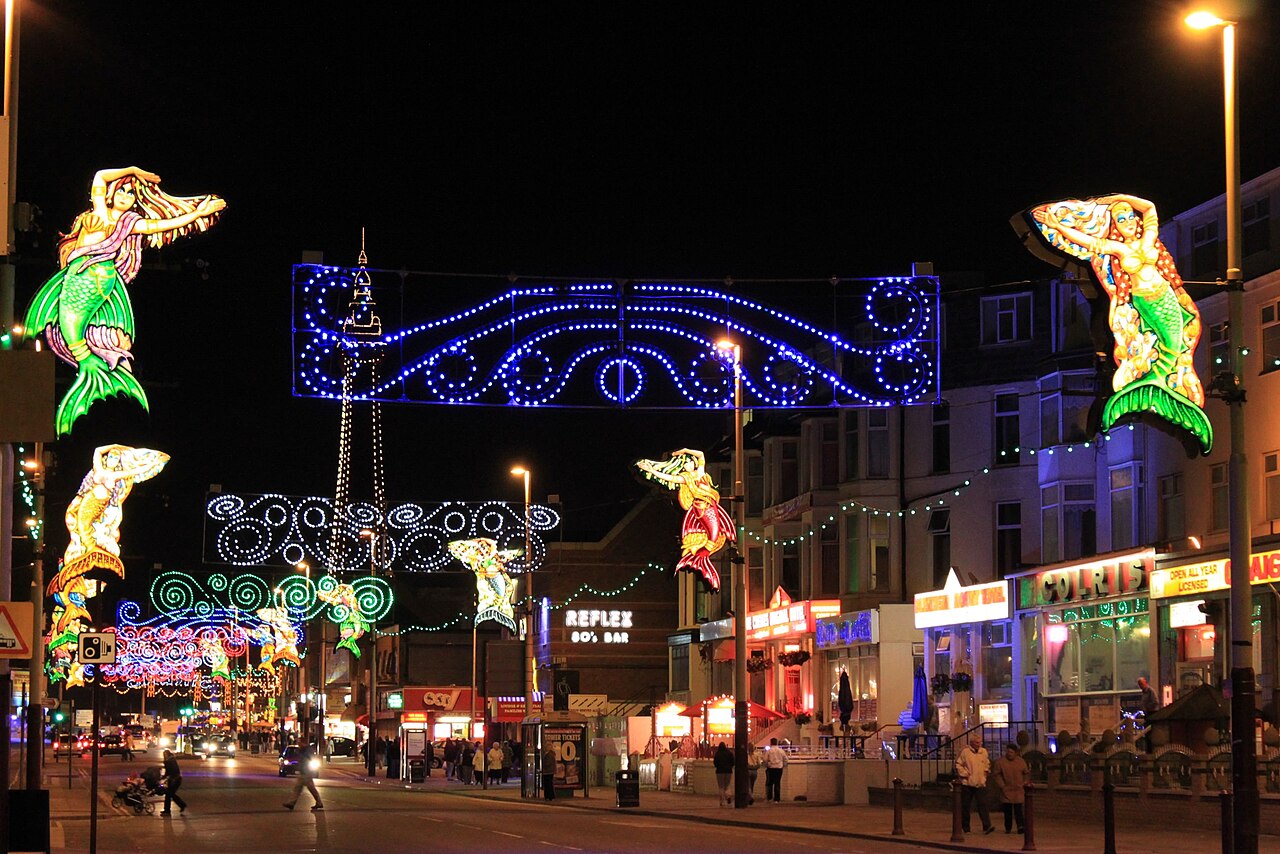 Illuminated mermaid tableaux spanning the street in Blackpool, with the Tower lit up in the background