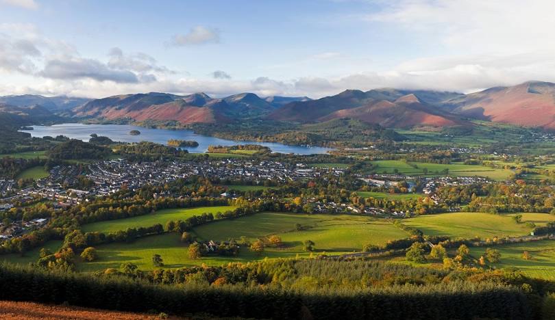 View over Keswick and Derwentwater from the fells, with autumn colours and mountains beyond