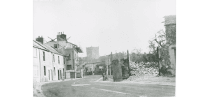 Tithebarn Street, looking south east with the church in the background. The demolished tithebarn and house to the right. A terrace of old houses to the left.
